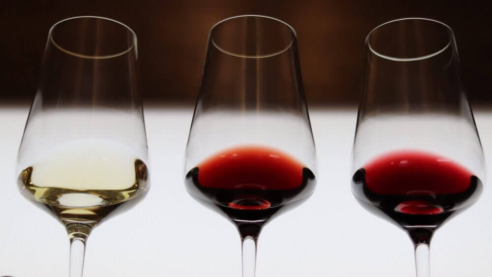 Trois verres de vin blanc et rouge alignés pour une dégustation pédagogique chez Sensation Vin.